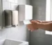 Uscător de mâini din inox și dispenser de prosoape de hârtie montate pe peretele unui grup sanitar de hotel